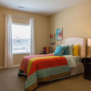 A cozy bedroom featuring colorful bedding and modern decor.