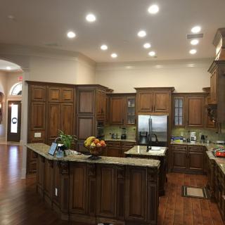 A spacious kitchen with wooden cabinets and a large island, featuring stainless steel appliances and recessed lighting.