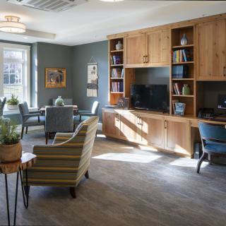 A modern office interior with bookshelves, desk, and chairs by a window.