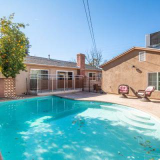 A sunny backyard featuring a swimming pool with patio chairs nearby.