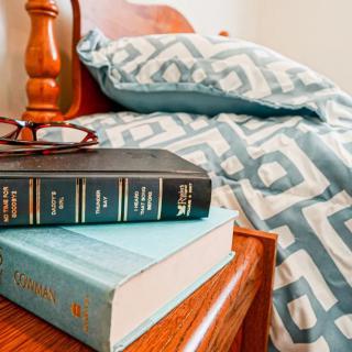 A cozy bedroom setting with books and glasses on the nightstand.