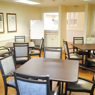 A well-lit dining room with multiple tables and chairs arranged neatly.