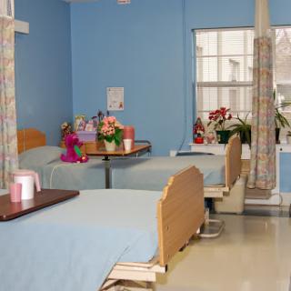 A clean and welcoming hospital patient room with two beds, decorated with flowers.