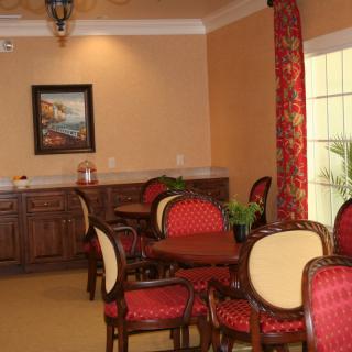 A cozy dining area with elegant chairs and tables, featuring warm decor and a painting on the wall.