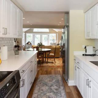 A modern kitchen with white cabinets and stainless steel appliances, leading to a cozy dining area.