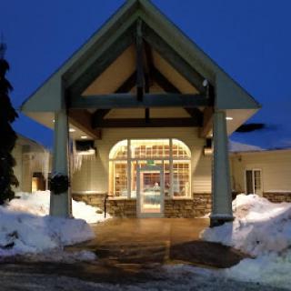 The welcoming entrance of a building illuminated at night, surrounded by snow.