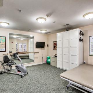 A well-equipped exercise room featuring a stationary bike, mirrors, and storage cabinets.