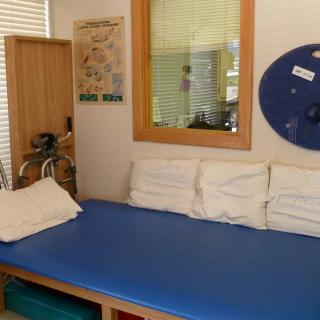 A therapy room with a blue treatment table and exercise equipment.