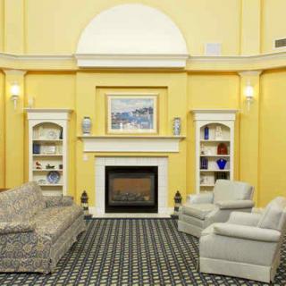 A cozy living room with yellow walls, featuring a fireplace, armchairs, a couch, and built-in shelves.