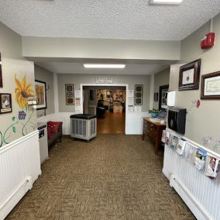 A welcoming interior view of a hallway leading to a common area, featuring decorative art and comfortable furnishings.