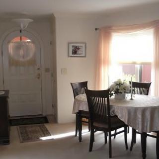 A cozy dining area with a table set near a large window, adorned with flowers and surrounded by chairs.