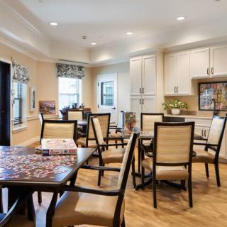 A modern dining area featuring multiple tables and chairs, with an open view to the kitchen space.