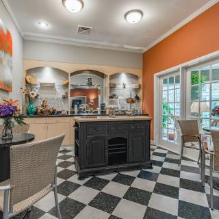 A stylish kitchen with checkered flooring and bright orange walls, featuring a central island and modern lighting.