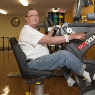 An elderly person is using exercise equipment indoors for rehabilitation and fitness.