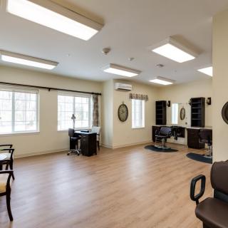 A spacious and well-lit salon interior with chairs, mirrors, and large windows.