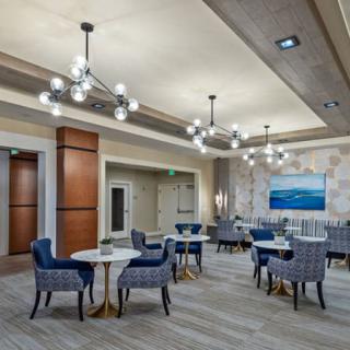 A modern lounge with elegant chandeliers, featuring comfortable seating and decorative artwork.