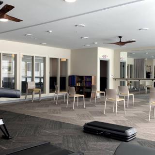 A spacious gym interior with exercise equipment, chairs, and mirrors.