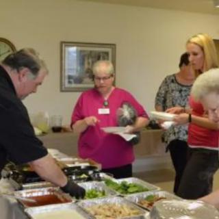 A group of people serving themselves from a buffet indoors.