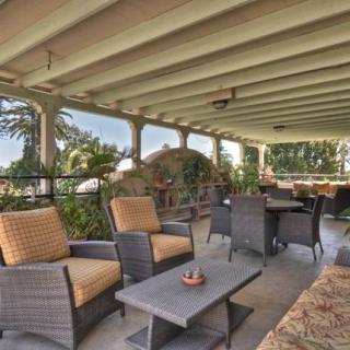 A cozy, covered patio with comfortable seating overlooking a lush garden.