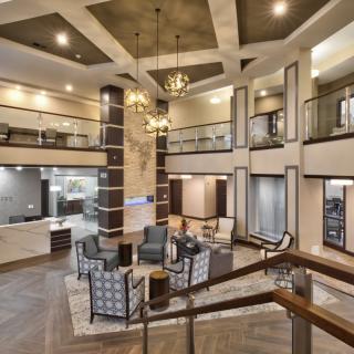 A spacious and elegantly designed lobby featuring modern furniture, stylish lighting, and an open mezzanine level.