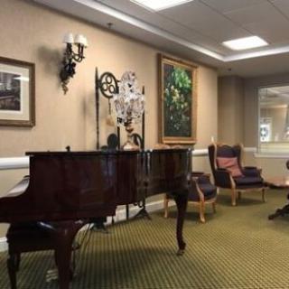 A cozy interior featuring a grand piano, comfortable seating, and elegant wall art.