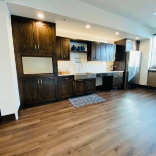 A modern kitchen with wooden cabinets and hardwood flooring, offering a spacious and minimalist design.