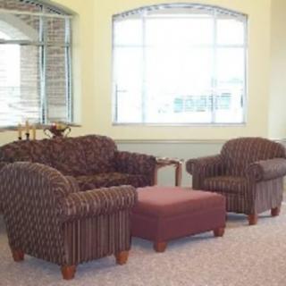 A cozy living room setup featuring a sofa, two armchairs, and a coffee table near a large window.