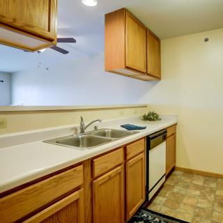 A well-lit kitchen featuring wooden cabinets, a dual sink, and modern appliances.