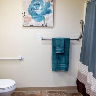 A well-decorated bathroom featuring teal towels and a matching floral painting.