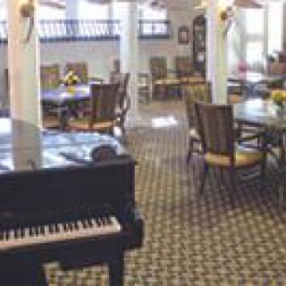 A dining area featuring tables and chairs, with a piano in the foreground.