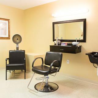 A modern hair salon interior featuring stylish black chairs and a vanity mirror.