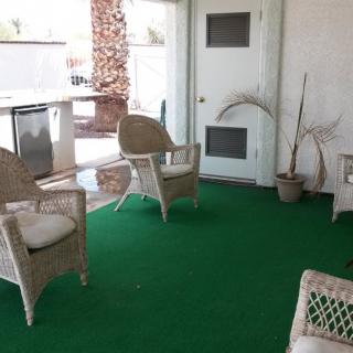 A cozy patio area with wicker chairs and green carpeting.