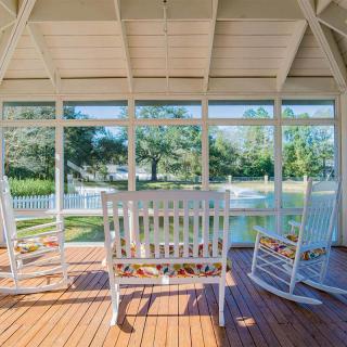 A cozy sunroom with rocking chairs and a wooden floor, offering a serene outdoor view.
