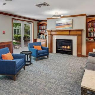 A cozy living room featuring a fireplace, blue chairs with orange cushions, and built-in bookshelves.