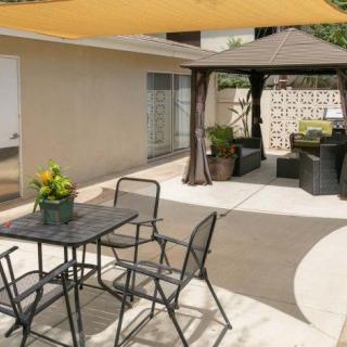A cozy patio with a shade sail, outdoor seating, and a gazebo offering an inviting space for relaxation.