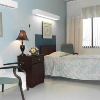A hospital room with a bed, nightstand, and chair.