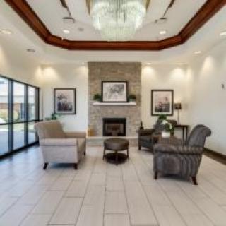 A modern lobby with armchairs around a fireplace, featuring elegant decor.