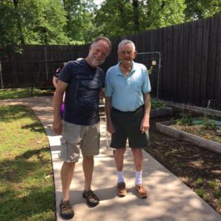 Two people standing on a path in a garden, enjoying a sunny day.