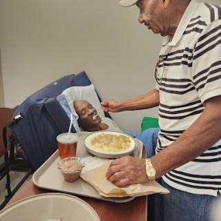A caring moment as a caregiver serves a meal to an elderly individual.