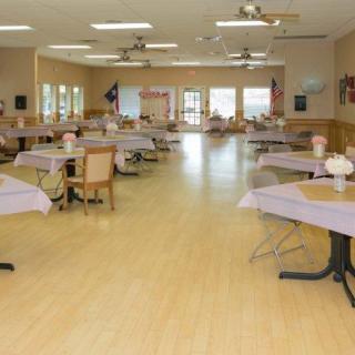A spacious dining hall with neatly arranged tables and chairs, ready for an event.