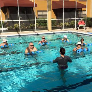 A group of people participating in a water aerobics class in an outdoor pool.