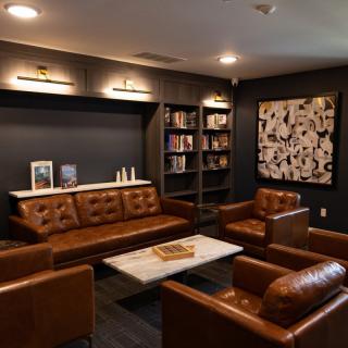 A cozy lounge with leather seating and a stylish bookshelf.