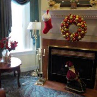 A cozy living room decorated for Christmas with a festive wreath and stockings hanging by the fireplace.
