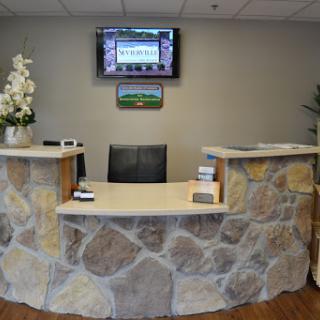 A modern reception area featuring a stone desk and a television, creating an inviting atmosphere.