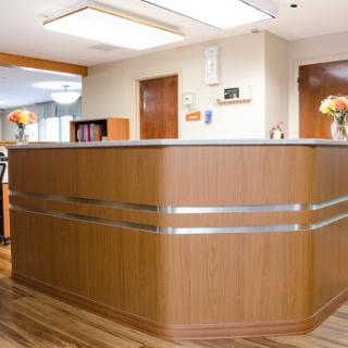 A modern reception area with a wooden desk and decorative flowers.