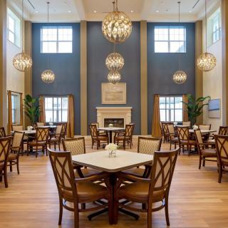 A well-decorated dining room with chandeliers, tables, and a fireplace.