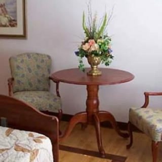 A cozy room corner featuring a round wooden table adorned with a decorative flower arrangement, flanked by two upholstered chairs.