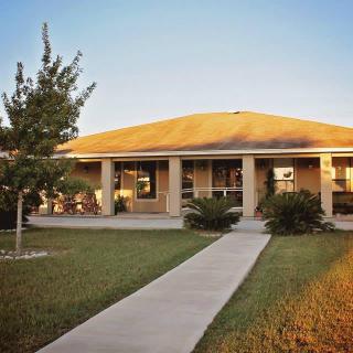 A suburban house with a walkway leading to the entrance, surrounded by a grassy yard.