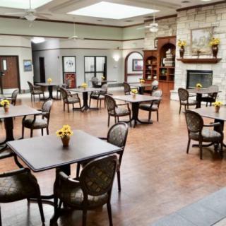A spacious dining area with tables and chairs, featuring a fireplace and wooden flooring.