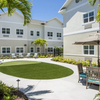A sunny courtyard with a landscaped garden, surrounded by a modern building.